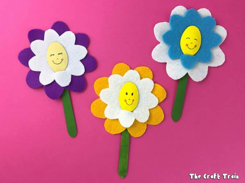 Happy flower craft from felt and wooden teaspoons on pink background #flowercrafts #kidscrafts #feltcrafts #Spring #Springcrafts