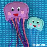 hand sewn jellyfish craft on blue sequin background #jellyfish #sewing #kidscraft #sewingpattern #kidsactivities #oceananimals #animalcrafts #jellyfishcraft #thecrafttrain