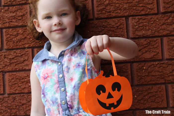 kid holding paper pumpkin basket