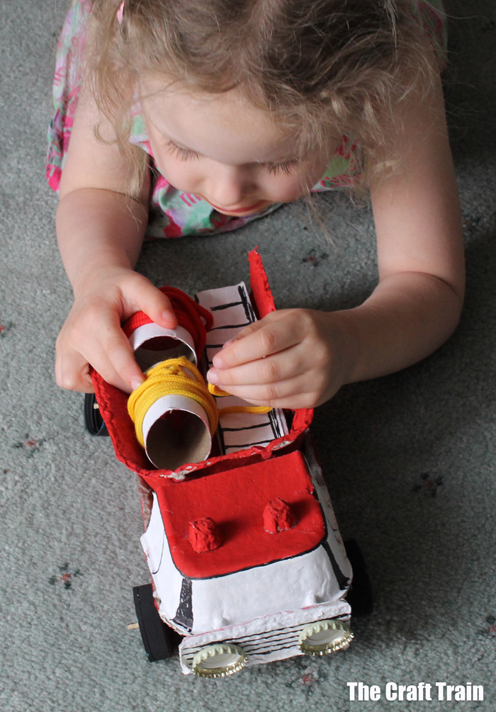 kid playing with egg carton fire truck