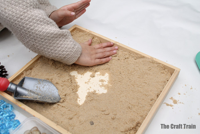 adding sand to the small world tray
